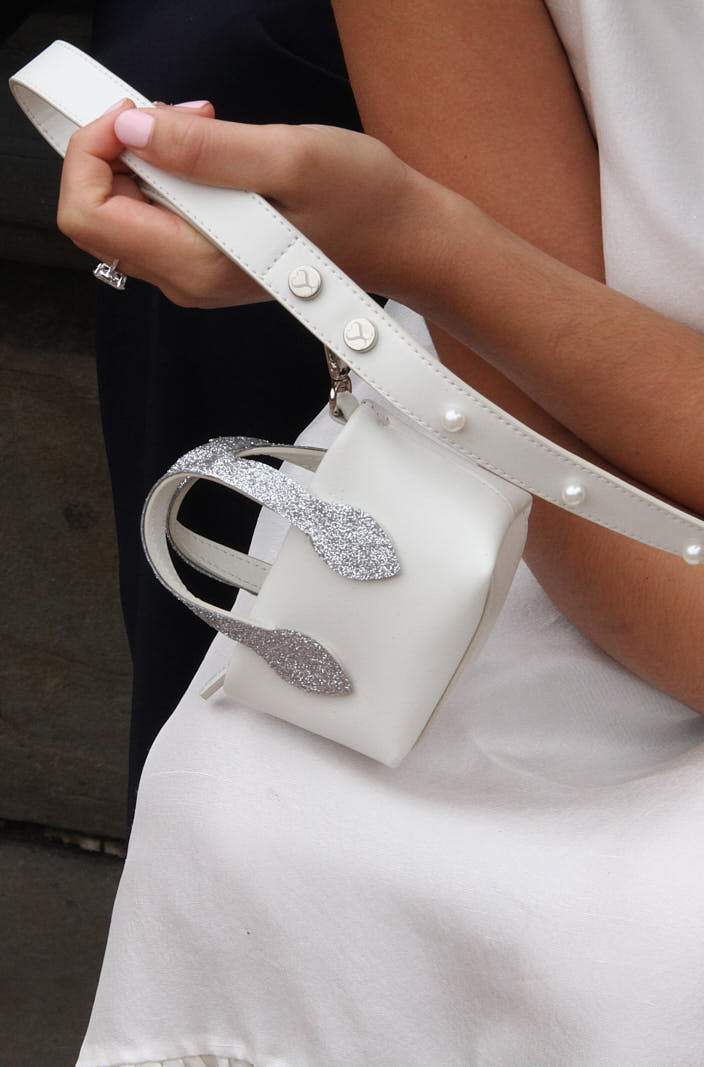 Essi pearl-studded white leash and Sloane Clean Up Purse held against a wedding dress